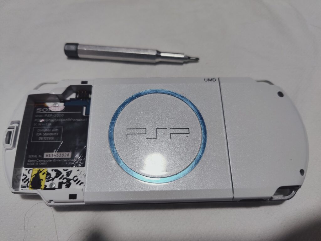 PSP 3000 laying on the table screen down. Battery bay is open. Process of PSP reshelling
